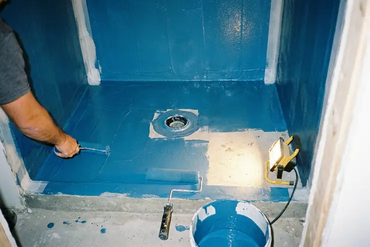 Natte d’étanchéité appliquée au sol et sur les murs d’une douche, avant la pose du carrelage